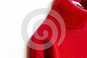 Red wool sweater hanging on clothes hanger on white background.close up