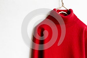 Red wool sweater hanging on clothes hanger on white background.close up