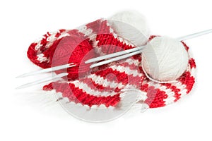 Red woolen scarf, knitting needles and balls of yarn