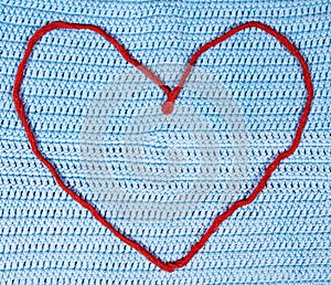 Red woolen string heart on crocheted cloth