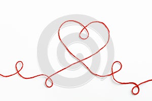 Red woolen thread in the shape of heart on white background