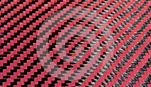 Red woven Black carbon fiber composite material background close up view