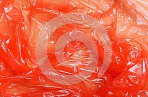 Red wrap, package polypropylene, plastic packaging on a beige background. Plastic pollution concept. Top view, flat lay
