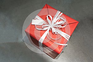 Red wrapped present box with white fancy bow tie and blank greet