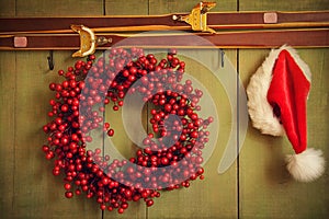 Red wreath with Santa hat hanging on rustic wall