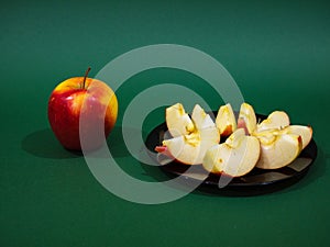 Red yellow apple and slice isolated on green background