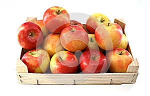 Red and yellow apples in a wooden crate on white background