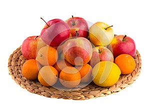 Red and yellow apples, tangerines and lemons on a straw mat