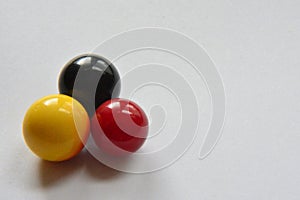 red, yellow and black marbles on white background