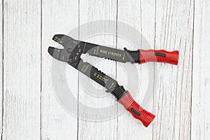 Red, yellow and black wire stripper tool weathered whitewash textured wood