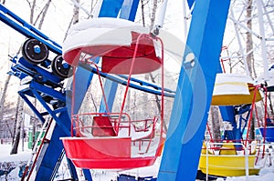 red and yellow booths of ferris wheel under the snow, out of gear