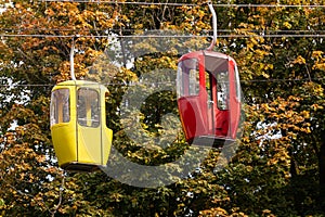 Red and yellow cable car cabins in autumn forest