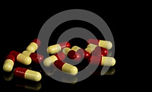 Red, yellow capsule pills on dark background. Antibiotic resi