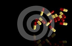 Red, yellow capsule pills on dark background. Antibiotic resi