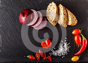 Red and yellow cherry tomatoes on slate with sliced bread, onion