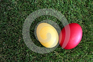 Red and yellow easter egg on green grass closeup