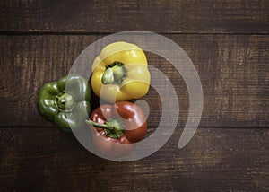 Red, Yellow and Green Bell Pepper on a Wood Plank Background