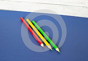 Red, yellow and green pencils on a wooden background