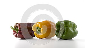 Red, yellow and green peppers in a row isolated on white background