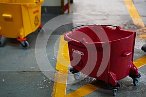 Red and yellow mop bucket and set of cleaning equipment in the office