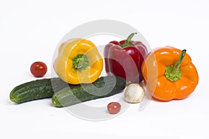Red yellow and orange peppers with tomatoes on a white background.