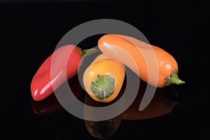 Red, yellow and orange sweet peppers isolated on black