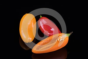 Red, yellow and orange sweet peppers isolated on black