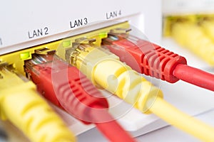 Red and yellow patch cords are inserted into the router of white color. home internet