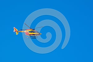 Red and yellow rescue helicopter moving in blue sky with blur pr