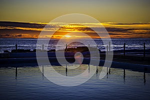 Red and yellow sunrise over ocean pool