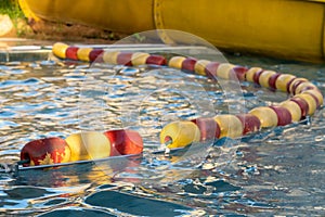 Red and yellow swimming safety buoys in a row for children`s protection in outdoor pool for deep end safety