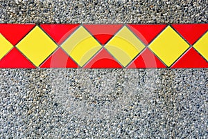 Red and yellow tiles on sand mixed with small stone wall texture background