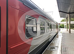 Red and yellow train wagon stand near platform on train station ready for departure.