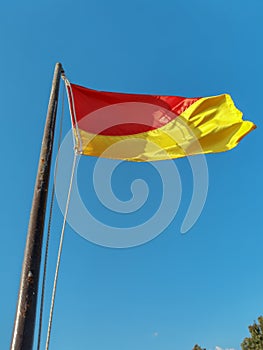 Red and yellow warning flag on the beach close up