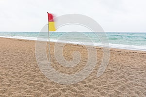 Red and yellow warning flag on a deserted beach