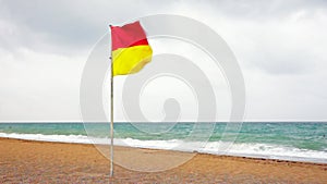 Red and yellow warning flag flying on a beach