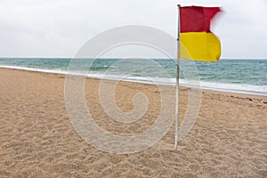 Red and yellow warning flag flying in the wind