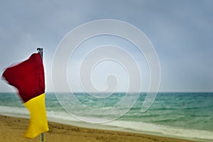 Red and yellow warning flag on a stormy beach