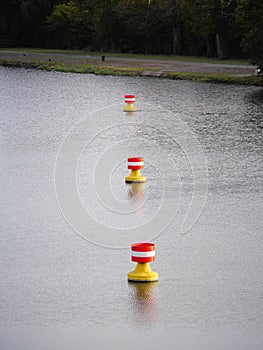 Red-yellow-white buoys drifting in the current on the water surface of a river