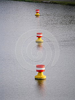 Red-yellow-white buoys drifting in the current on the water surface of a river