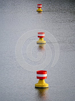 Red-yellow-white buoys drifting in the current on the water surface of a river