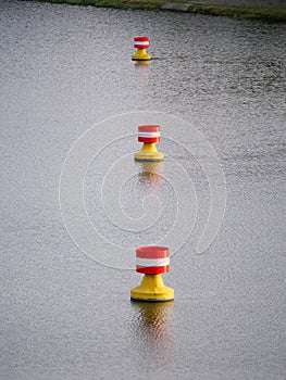 Red-yellow-white buoys drifting in the current on the water surface of a river