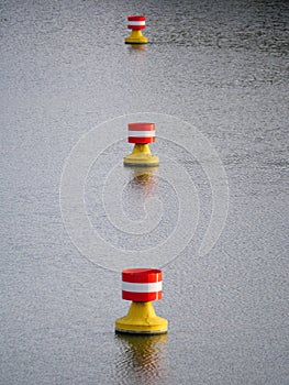 Red-yellow-white buoys drifting in the current on the water surface of a river