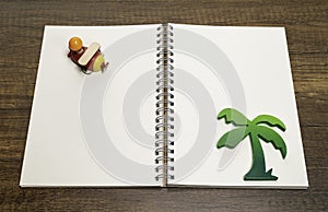 Red and yellow wooden airplane on blank white notebook with green palm tree