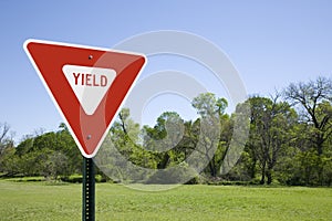 Red Yield Sign in a Green Landscape, Blue Sky