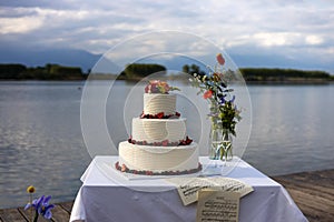 redberries wedding cake with flowers in a lake landscape photo