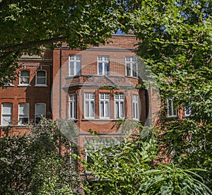 A redbricked house and green trees.