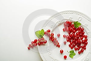 Redcurrant berries in a plate on white background