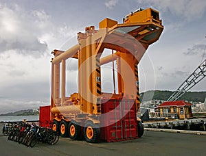 Redevelopment of seashore with decommissioned yellow straddle carrier and bicycles on waterfront wharf, Wellington, New Zealand