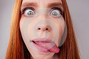 Redhair ginger woman demonstrating tongue and making stupid face with crossed eyes